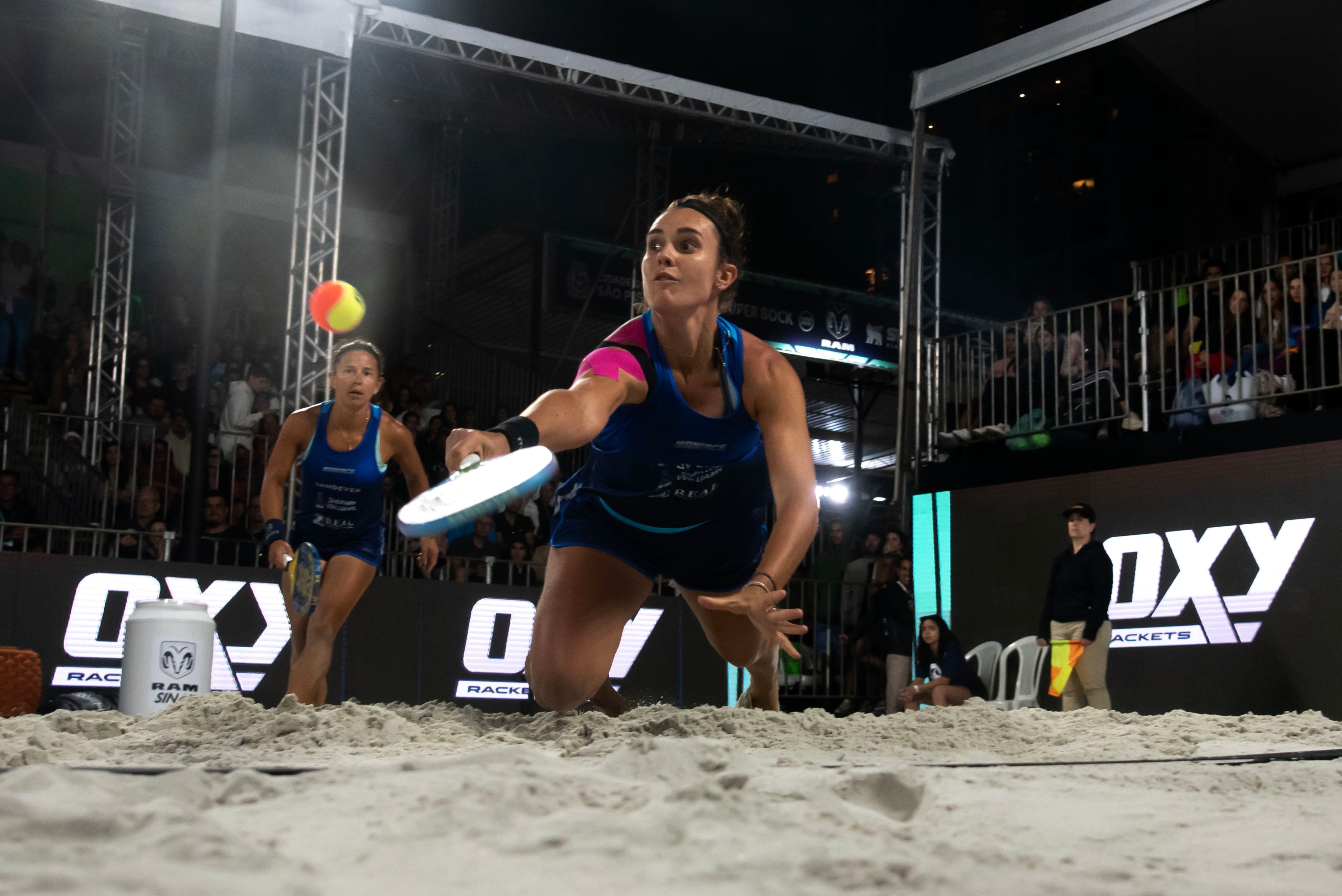 jogadora de beach tennis mergulha para defender uma bola